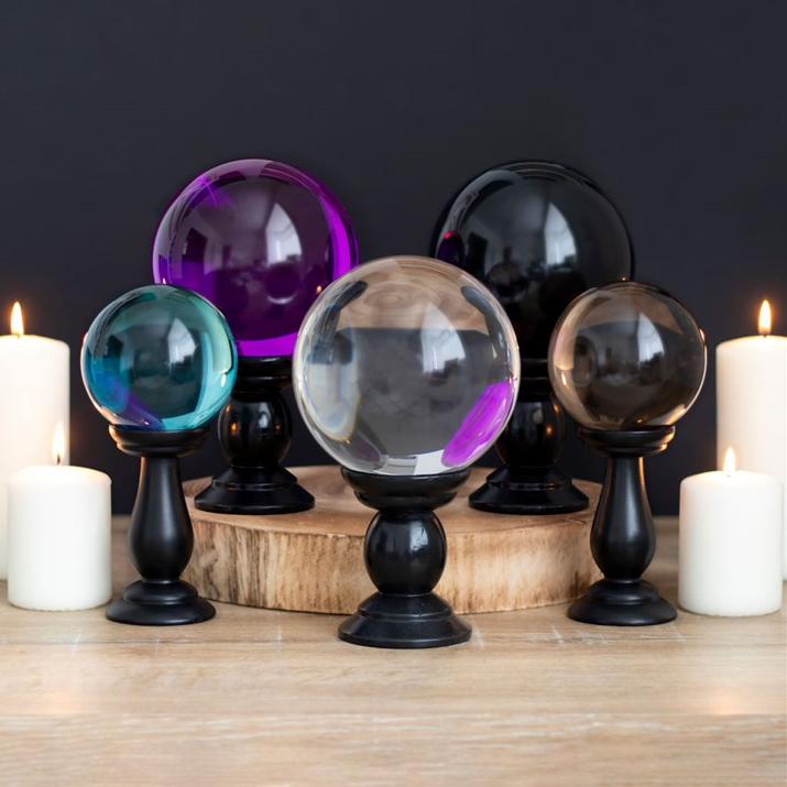 Set of colorful glass spheres on stands with candles in the background