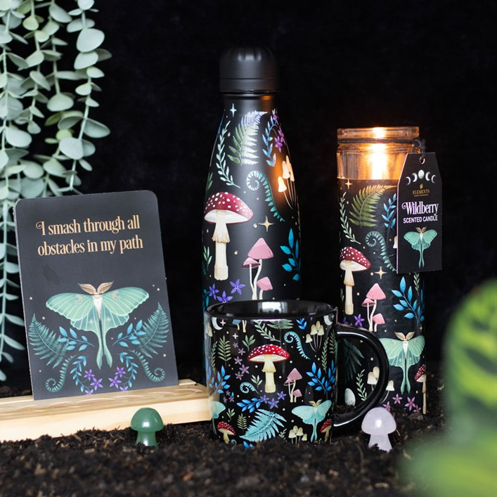 Set of mushrooms-themed products including a bottle, mug, and candle on a dark background.