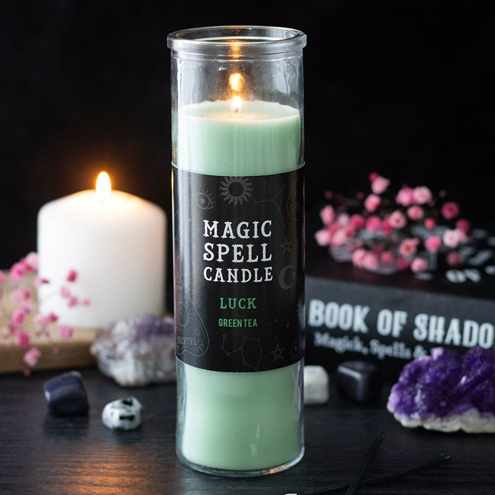 Green spell candle with a label on a dark background