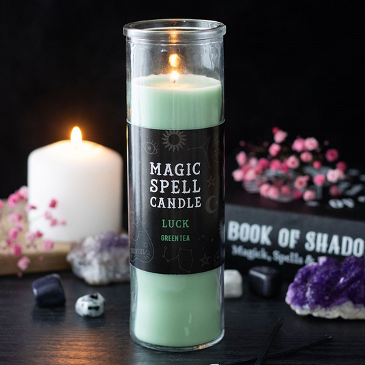 Green spell candle with a label on a dark background