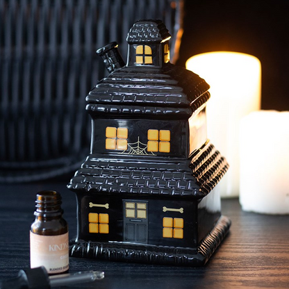 Halloween-themed house-shaped lantern with candles on a wooden surface