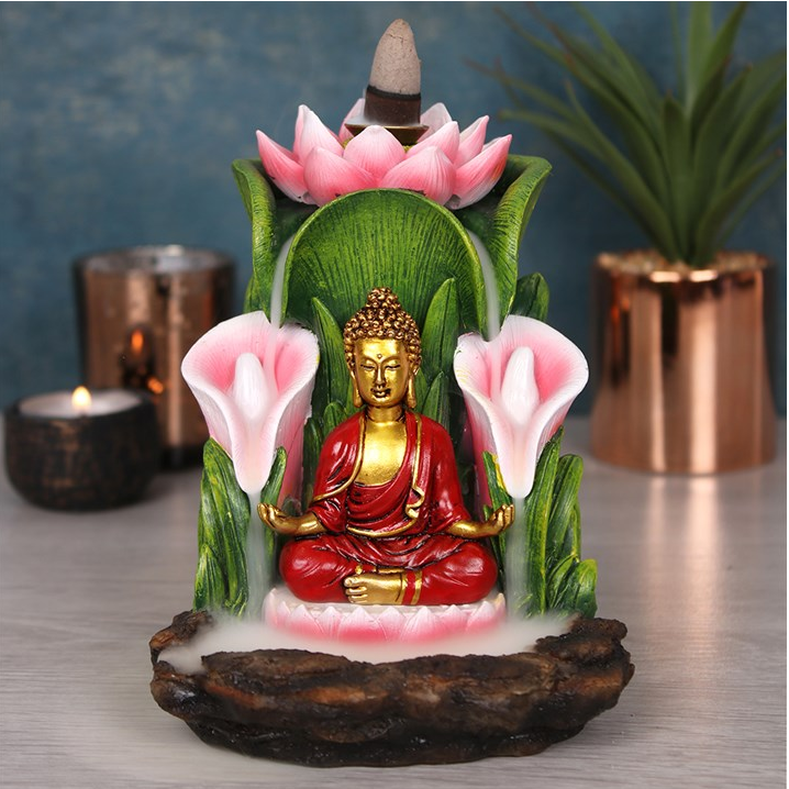 Decorative Buddha statue with flowers and a candle on a reflective surface.