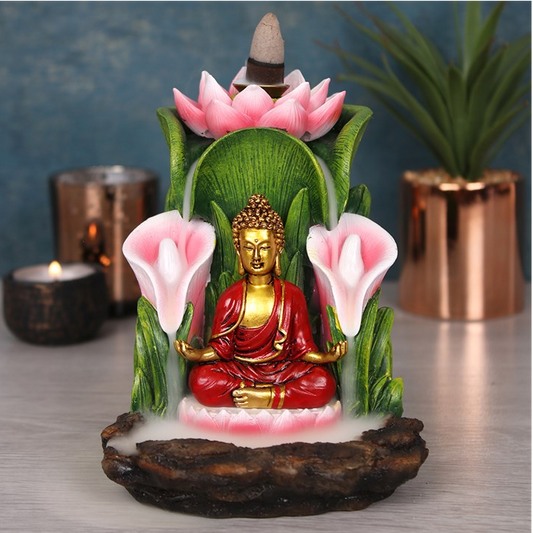 Decorative Buddha statue with flowers and a candle on a reflective surface.