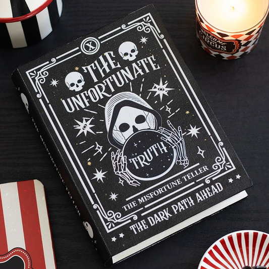 Book titled 'The Unfortunate Truth' with skull and crossbones design on a dark surface.