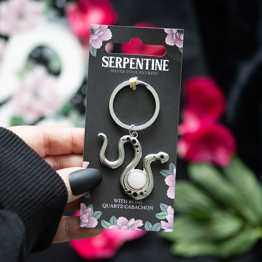 Serpentine keychain packaging held by a hand with a floral background