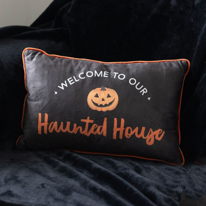 Halloween-themed pillow with text and pumpkin graphic on a dark background
