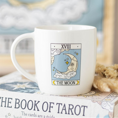 White mug with 'The Moon' tarot card design on a book titled 'The Book of Tarot'.
