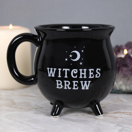 Black mug with 'Witches Brew' text on a marble surface with candles in the background