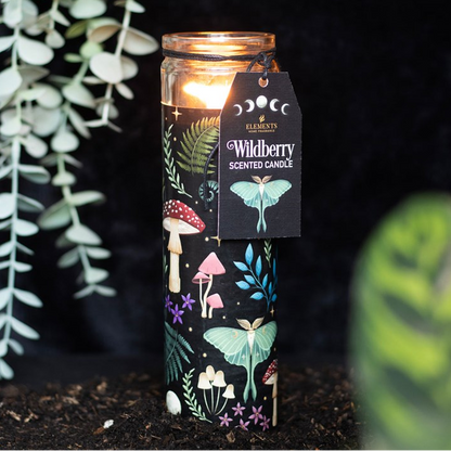 Decorative candle with mushroom design and 'Wildberry' label, surrounded by greenery.