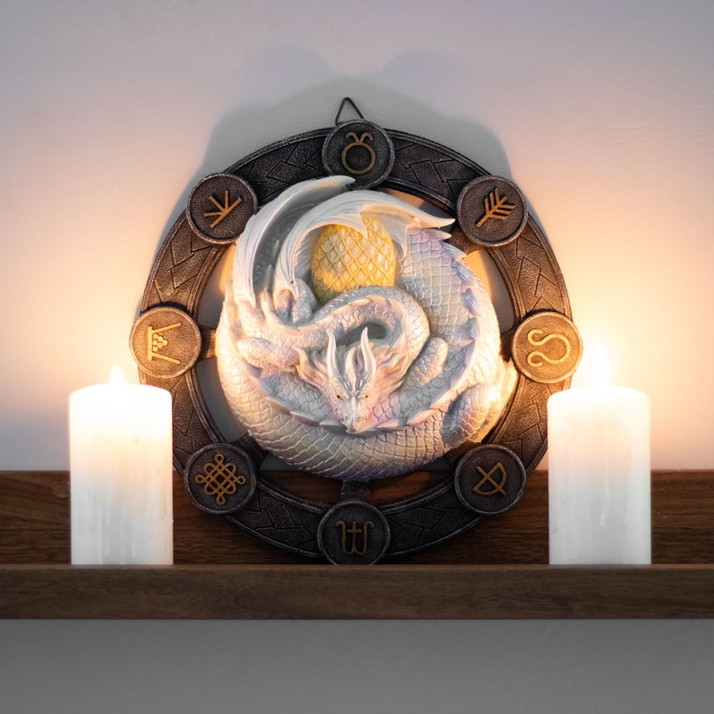 Decorative wall art with a design and candles on a wooden shelf.