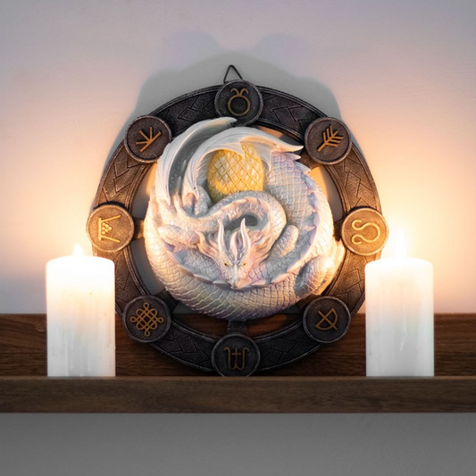 Decorative wall art with a design and candles on a wooden shelf.
