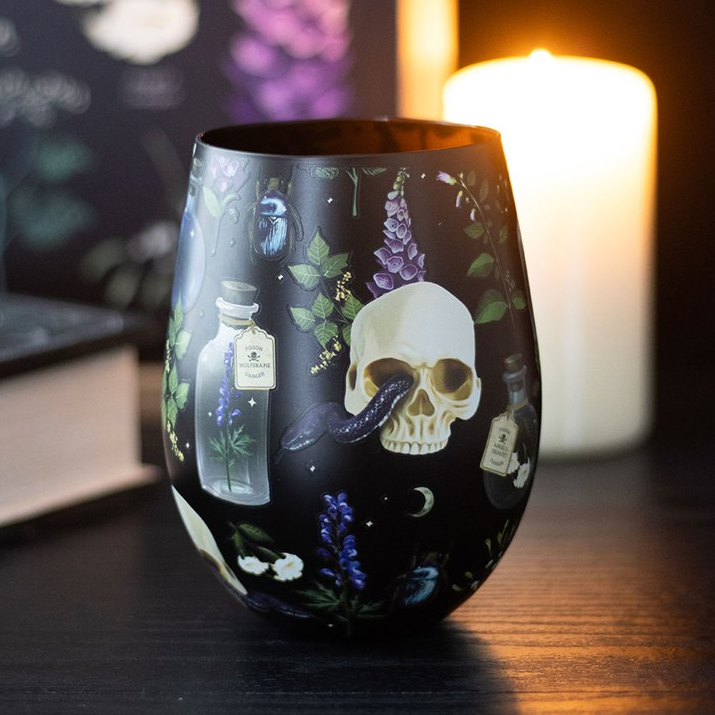 Decorative glass with skull and potion design on a dark background