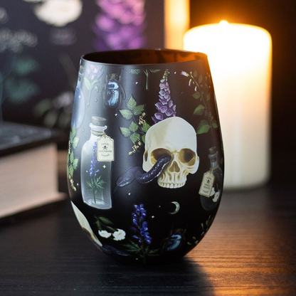 Decorative glass with skull and potion design on a dark background