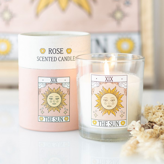 Rose scented candle labeled 'The Sun' with packaging on a white surface.