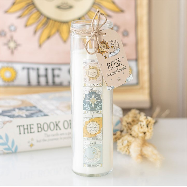 Rose-scented candle in a glass jar with a decorative tag on a surface.