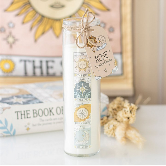 Rose-scented candle in a glass jar with a decorative tag on a surface.