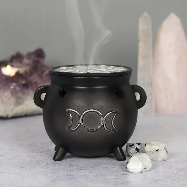 Black cauldron incense burner with three moon symbols on a neutral background