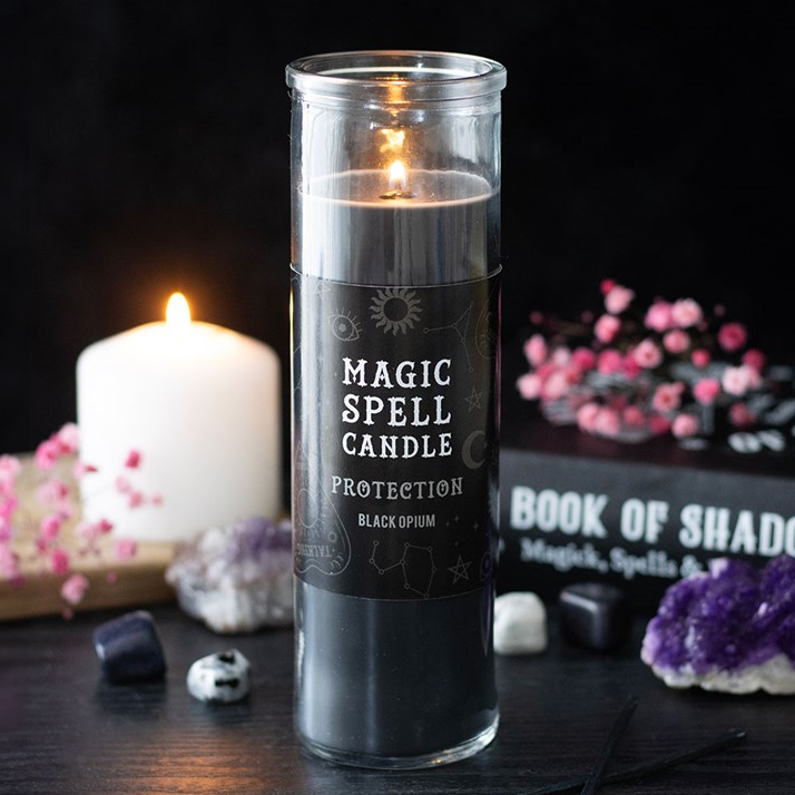 Magic spell candle labeled 'Protection' with decorative items on a dark surface