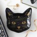 Black cat-shaped dish with gold accents on a white surface