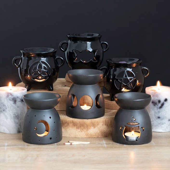 Set of black ceramic oil burners with decorative designs on a wooden surface.