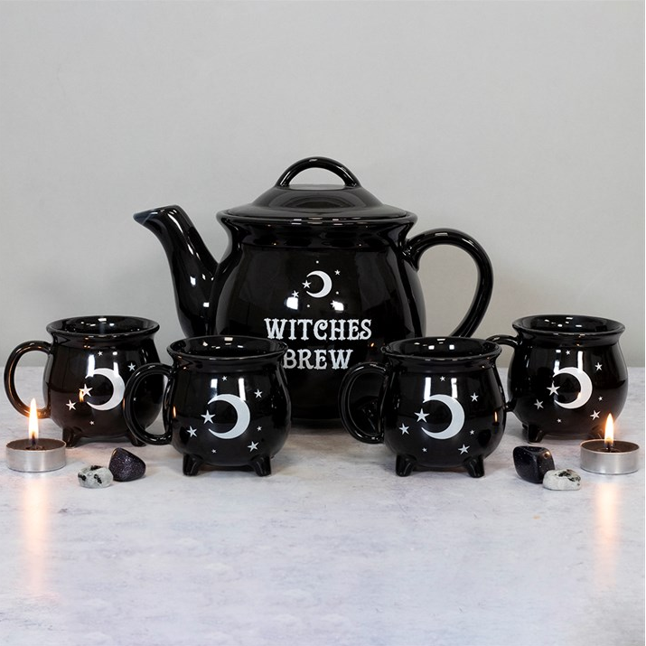 Black ceramic teapot and mugs with 'Witches Brew' text on a light background