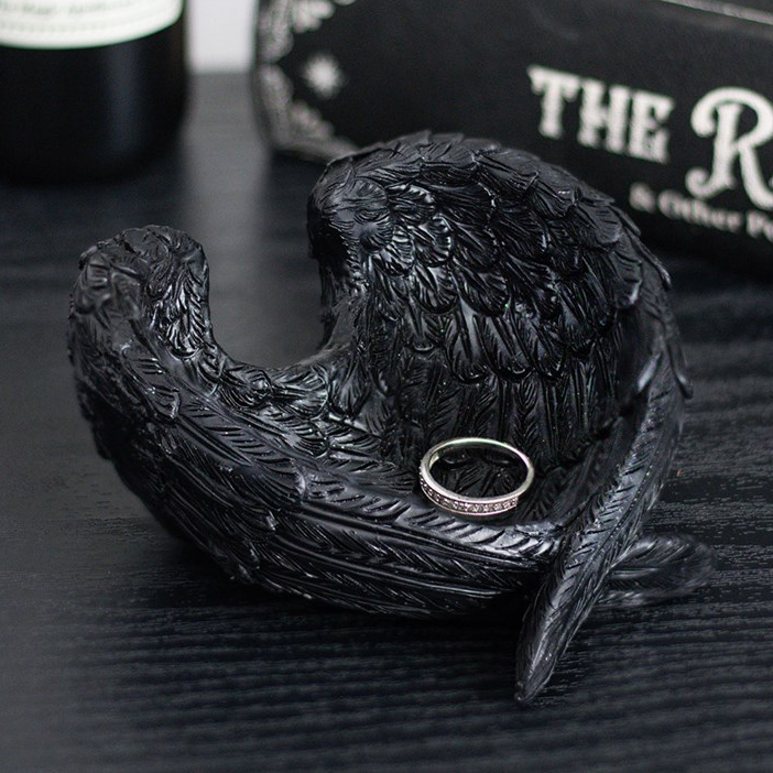 Black decorative angel wing dish with a ring on a dark surface