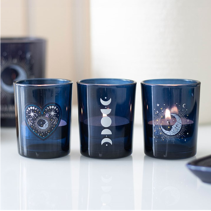 Three blue glass tumblers with decorative designs on a white surface.