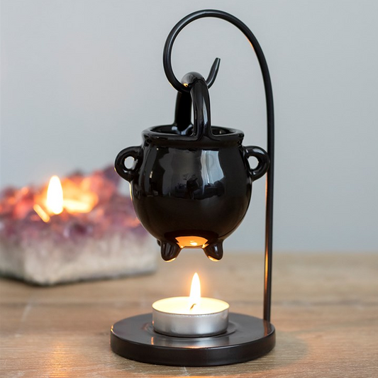 Black metal candle holder with a small candle on a wooden surface.
