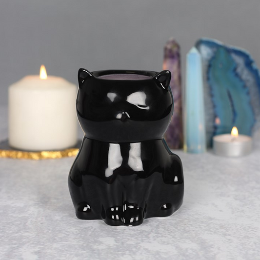 Black cat-shaped candle holder on a gray surface with candles and crystals in the background.
