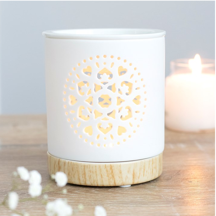 White ceramic candle holder with wooden base on a wooden surface