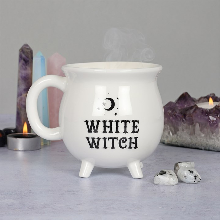 White mug with 'White Witch' text on a gray surface with candles and crystals in the background