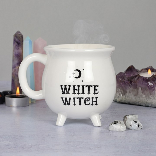 White mug with 'White Witch' text on a gray surface with candles and crystals in the background