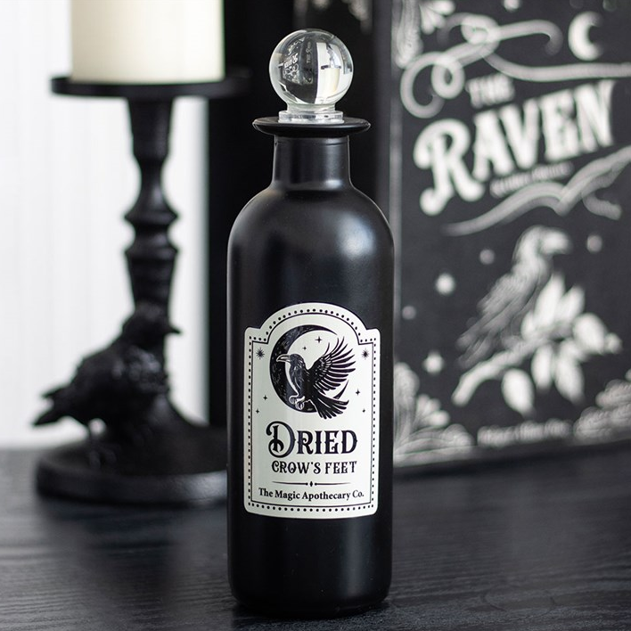 Black bottle labeled 'Dried Crow's Feet' with decorative background featuring a candle and 'The Raven' book.