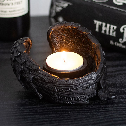 Decorative black candle holder with a lit candle on a dark surface.