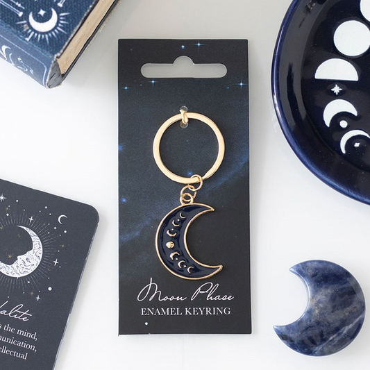 Moon phase enamel keyring on a card with packaging and decorative items.