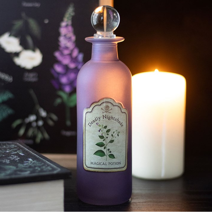 Purple potion bottle labeled 'Magical Potion' next to a lit candle on a dark background