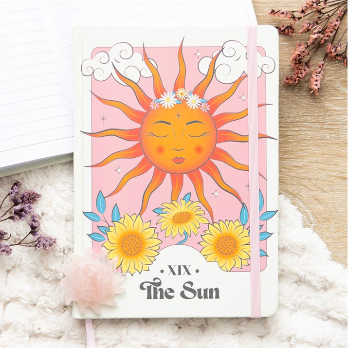 Card with a sun illustration and flowers on a white surface with floral decorations.