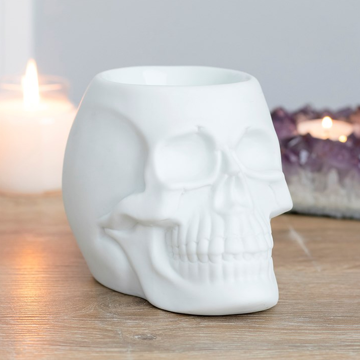 White skull-shaped candle holder on a wooden surface with soft lighting