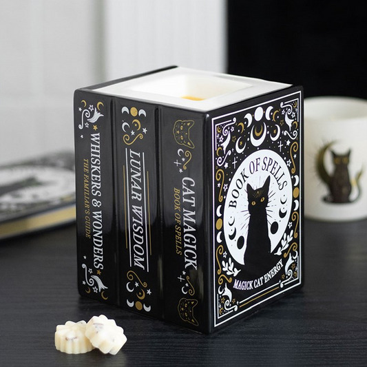 Candle in a decorative box with cat-themed design on a dark surface.
