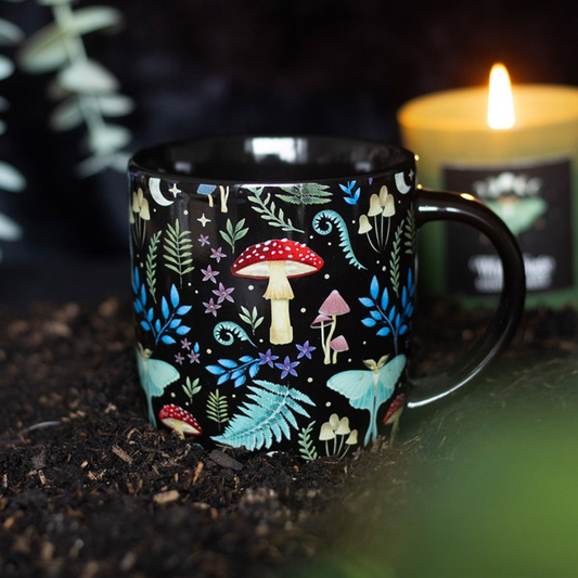 Mug with nature-themed design on a dark background with a candle