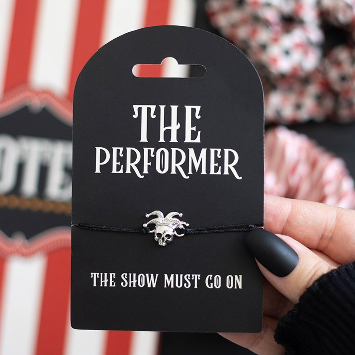 Black packaging with 'The Performer' text and a small decorative item, held by a hand.