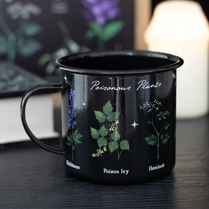 Black mug with botanical illustrations and text on a dark surface