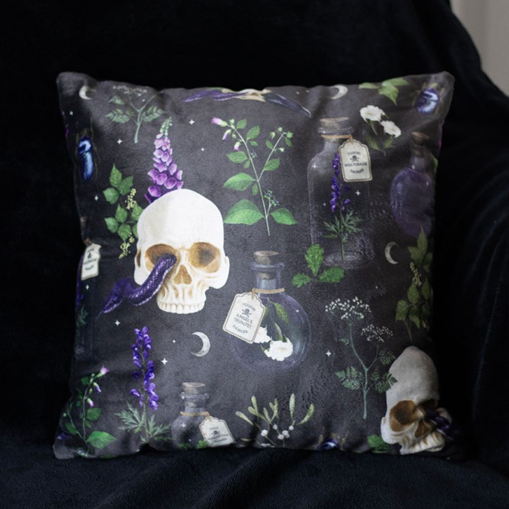 Decorative pillow with skull and botanical design on a dark background