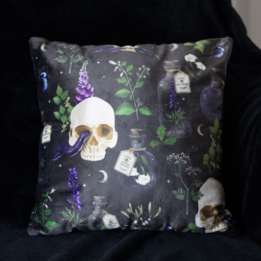 Decorative pillow with skull and botanical design on a dark background