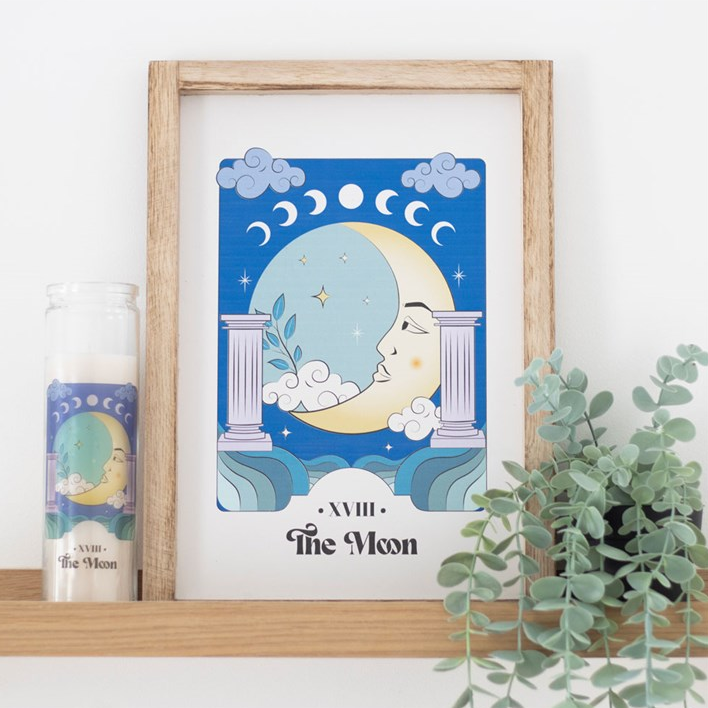 Framed artwork of a moon design on a shelf with a candle and plant.