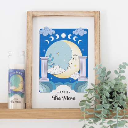 Framed artwork of a moon design on a shelf with a candle and plant.