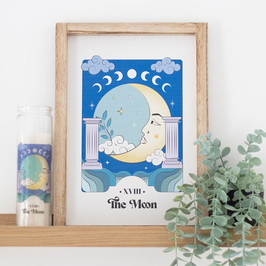 Framed artwork of a moon design on a shelf with a candle and plant.