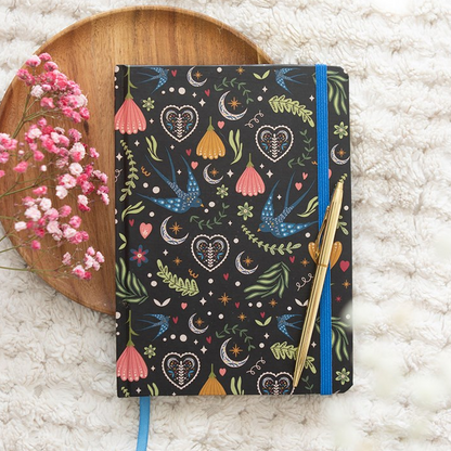 Notebook with colorful patterns on a textured surface with flowers and a wooden coaster.