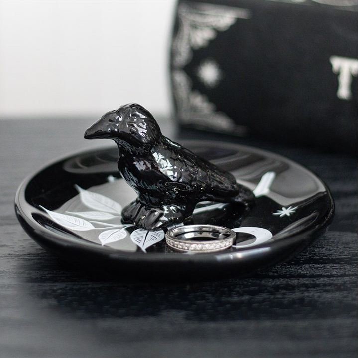 Black bird-shaped ring holder with rings on a dark surface