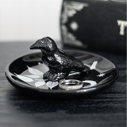 Black bird-shaped ring holder with rings on a dark surface
